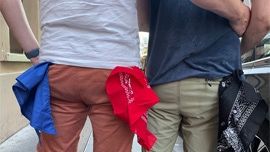Deux hommes vus de dos se tenant par les hanches portent aux poches de leur pantalon, des bandanas. Une photo qui illustre les codes de dragues gay appelés The Scarf Code ("Hanky Code")