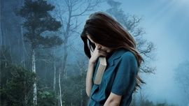 Une personne triste, au milieu du brouillard qui tient contre elle un livre, montre son mal être
