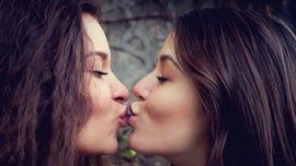 2 femmes devant un murs qui s'embrassent sur la bouche, 2 lesbiennes qui ont fait leur coming-out et s'assument